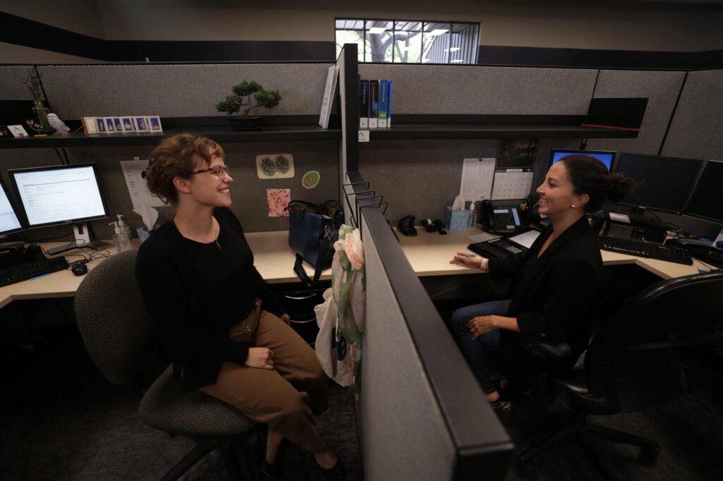 Two Atchley & Associates team members talking at adjoining office workstations